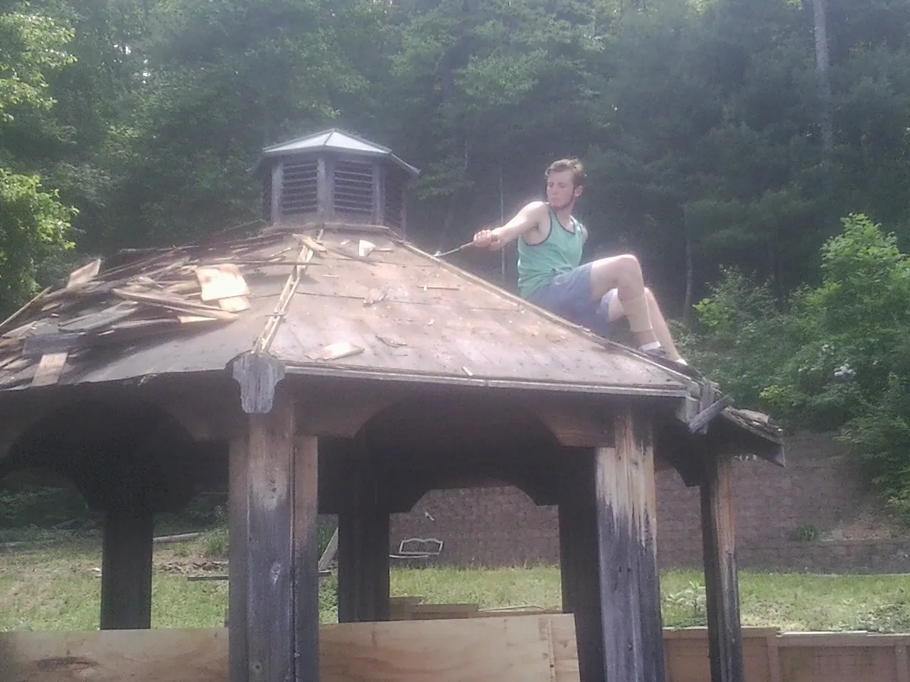 Tearing the old roof off a wooden gazebo before new shakes in Arnold