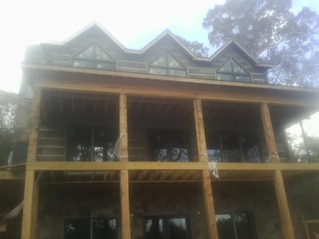 Dormers and porch framing on a large log home under construction — Roof Coating work by our crew in Arnold