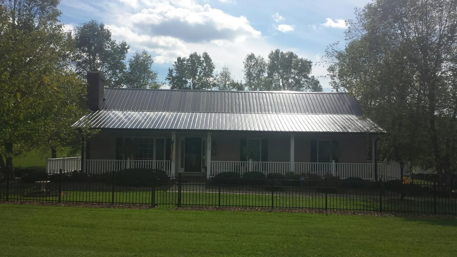 Gray metal roof on a brick ranch with a full width front porch — Gutter Guard Installation work by our crew in Arnold
